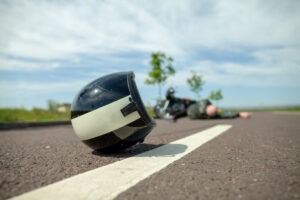 Helmet lies at scene of accident with injured motorcyclist in background