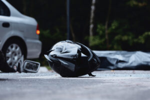 A motorcycle helmet lies on the road after a crash with a vehicle. What is a major cause of death in motorcycle accidents?