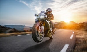 A motorcyclist performs a wheelie stunt on an open highway.