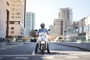 A motorcyclist stops at an intersection in broad daylight.