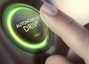 A driver presses a bright green autonomous driving button.