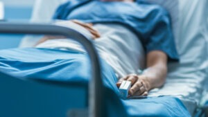 A hospital patient rests in bed with a heart monitor.