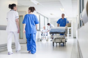 Medical staff bring a crash cart down a hospital hallway.