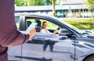 A rideshare passenger with a phone approaches a driver for a ride.