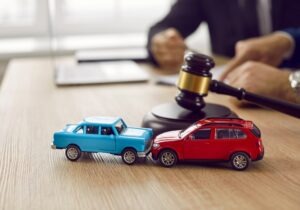 A lawyer with wrecked toy cars. Go over how much it costs to hire a car accident lawyer today. 