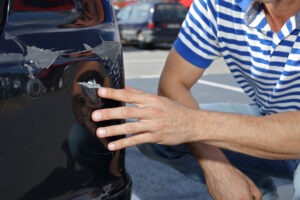 A parking lot accident lawyer in Indianapolis inspects a damaged vehicle to determine fault in a parking lot accident.