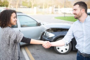 People shaking hands after a car accident. Talk to us to find out how a car accident settlement works. 