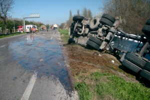 A truck lies on its side in the road after a dangerous accident with a private vehicle.