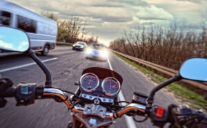 A motorcyclist barrels toward a head-on collision with a car.