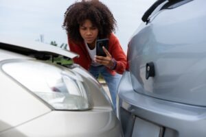 A woman taking pictures after a crash and wondering what happens if your Uber is in an accident. 