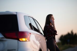 A woman by the side of a vehicle wondering what to do if her Uber driver was high and got into a wreck. 