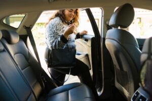 A young woman climbs into her Uber.