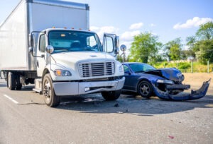 A damaged car and truck sit on the side of the road after a head-on collision.