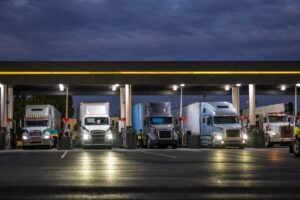 Several trucks pull into a truck stop at night.