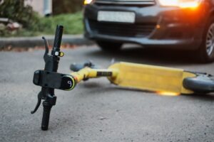 Yellow electric scooter lies on the ground after crash. Accident with car and electric scooter.