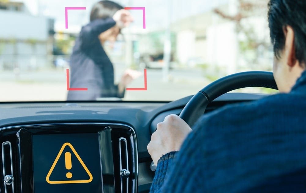 Driver's view of a pedestrian detection warning system alerting to a person ahead in the roadway avoiding a pedestrian accident in Indianapolis